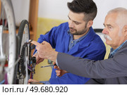 Mechanic checking chain tautness on bicycle. Стоковое фото, агентство Ingram Publishing / Фотобанк Лори