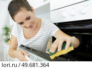 a woman cleaning household oven. Стоковое фото, агентство Ingram Publishing / Фотобанк Лори