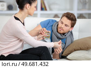 girlfriend taking care of ill boyfriend on the sofa. Стоковое фото, агентство Ingram Publishing / Фотобанк Лори