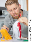 young man repairing iron inhis workspace. Стоковое фото, агентство Ingram Publishing / Фотобанк Лори