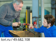 apprentice in a factory using a hammer. Стоковое фото, агентство Ingram Publishing / Фотобанк Лори