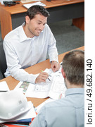 two men discussing blueprints in the office. Стоковое фото, агентство Ingram Publishing / Фотобанк Лори