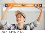 happy woman measuring level of ceiling. Стоковое фото, агентство Ingram Publishing / Фотобанк Лори