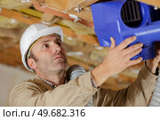 a male builder fixes a ventilation box. Стоковое фото, агентство Ingram Publishing / Фотобанк Лори
