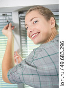 woman adjusting a window blind with a screwdiver. Стоковое фото, агентство Ingram Publishing / Фотобанк Лори