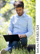 businessman sitting on the grass is working on laptop. Стоковое фото, агентство Ingram Publishing / Фотобанк Лори