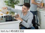 man on wheelchair cooking meal. Стоковое фото, агентство Ingram Publishing / Фотобанк Лори