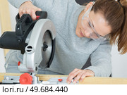 young female carpenter is using a circular saw. Стоковое фото, агентство Ingram Publishing / Фотобанк Лори