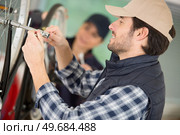 man tightening axle on bicycle wheel using a socket wrench. Стоковое фото, агентство Ingram Publishing / Фотобанк Лори
