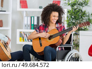 disabled young woman playing guitar at home. Стоковое фото, агентство Ingram Publishing / Фотобанк Лори