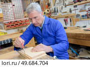 senior carpenter using brush on piece of wood in workshop. Стоковое фото, агентство Ingram Publishing / Фотобанк Лори