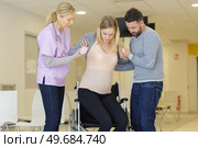 smiling nurse assisting woman to get up from wheelchair. Стоковое фото, агентство Ingram Publishing / Фотобанк Лори