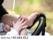 Baby in stroller demonstrates early development stage - hand-foot interaction, a precursor to crawling. Стоковое фото, фотограф Татьяна Степанищева / Фотобанк Лори