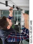 senior man installing a ceiling light. Стоковое фото, агентство Ingram Publishing / Фотобанк Лори