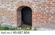 Small metal door in wall of ancient castle. Arched opening in wall of brick building. Massive heavy door with wrought iron details. Стоковое фото, фотограф Ирина / Фотобанк Лори