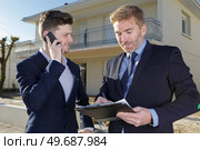 suited men with clipboard and smartphone outside a residential property. Стоковое фото, агентство Ingram Publishing / Фотобанк Лори