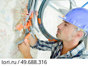 Builder holding cables together with tape & ties. Стоковое фото, агентство Ingram Publishing / Фотобанк Лори