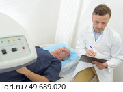 doctor checking medical record of his patient during a scan. Стоковое фото, агентство Ingram Publishing / Фотобанк Лори