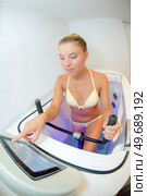 Lady using exercise machine in water bath, touching control screen. Стоковое фото, агентство Ingram Publishing / Фотобанк Лори
