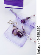 trendy author necklace with rarely gemstone charoite and earrings with purple agate around white background. fashion and handmade concept. Стоковое фото, агентство Ingram Publishing / Фотобанк Лори