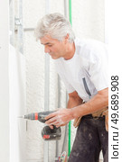 male worker is drilling into the wall. Стоковое фото, агентство Ingram Publishing / Фотобанк Лори