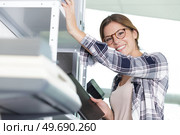 woman by racking in office holding notebook. Стоковое фото, агентство Ingram Publishing / Фотобанк Лори