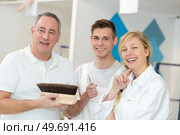 team of young workers in hardhats painting the wall. Стоковое фото, агентство Ingram Publishing / Фотобанк Лори