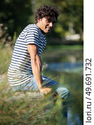 young man sitting on a pontoon by a lake. Стоковое фото, агентство Ingram Publishing / Фотобанк Лори