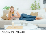 Lady layed on couch, holding cellphone. Стоковое фото, агентство Ingram Publishing / Фотобанк Лори