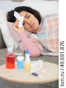 poorly woman on sofa with medication on side-table. Стоковое фото, агентство Ingram Publishing / Фотобанк Лори