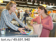 young female store clerk serving purchaser at cash desk. Стоковое фото, агентство Ingram Publishing / Фотобанк Лори