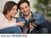 man and woman looking back over photos on their camera. Стоковое фото, агентство Ingram Publishing / Фотобанк Лори