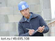 man builder writing on clipboard outdoors. Стоковое фото, агентство Ingram Publishing / Фотобанк Лори