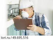 man wearing dust mask making report on renovation property. Стоковое фото, агентство Ingram Publishing / Фотобанк Лори