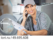 female contractor repairing washing machine at home. Стоковое фото, агентство Ingram Publishing / Фотобанк Лори