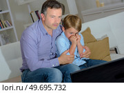 Father comforting boy scared watching television. Стоковое фото, агентство Ingram Publishing / Фотобанк Лори