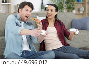 cheerful couple relaxing together on couch playing videogame. Стоковое фото, агентство Ingram Publishing / Фотобанк Лори