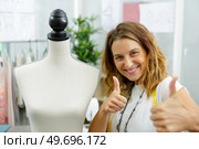 portrait of a seamstress at her workplace showing thumbs up. Стоковое фото, агентство Ingram Publishing / Фотобанк Лори