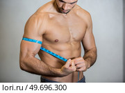 man measures bicep with measuring tape. Стоковое фото, агентство Ingram Publishing / Фотобанк Лори