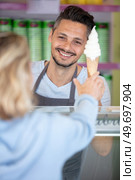 confectioner selling ice cream to young woman in the shop. Стоковое фото, агентство Ingram Publishing / Фотобанк Лори