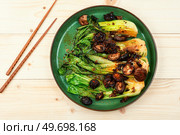 Fried Pak Choi with shitake mushrooms and chopstick on wooden table. Fried Chinese cabbage pak choi. Стоковое фото, агентство Ingram Publishing / Фотобанк Лори