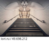Subway corridor with white tile on walls and glowing lights above a the stairs passage. Symmetrical underground staircase. Стоковое фото, агентство Ingram Publishing / Фотобанк Лори
