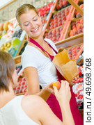 Shop assistant passing apricot to customer. Стоковое фото, агентство Ingram Publishing / Фотобанк Лори