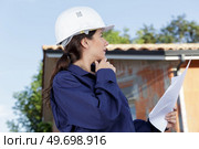 female builder wearing overalls stood outside a property holding paperwork. Стоковое фото, агентство Ingram Publishing / Фотобанк Лори