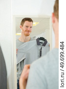 young man trying on clothes in clothing store. Стоковое фото, агентство Ingram Publishing / Фотобанк Лори