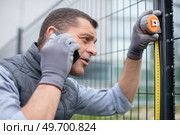handy man measuring fence while calling on phone. Стоковое фото, агентство Ingram Publishing / Фотобанк Лори