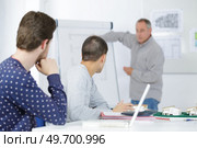 2 students with notebook listening to the teacher in classroom. Стоковое фото, агентство Ingram Publishing / Фотобанк Лори
