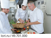 head chef teaching his colleagues how to slice vegetables. Стоковое фото, агентство Ingram Publishing / Фотобанк Лори