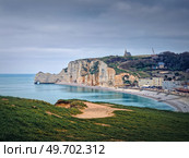 Sightseeing view to Etretat coastline with the famous Notre-Dame de la Garde chapel on the Amont cliff. Seashore washed by Atlantic ocean waters, Normandy, France. Стоковое фото, агентство Ingram Publishing / Фотобанк Лори