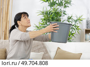 woman at home catching a leak in a bucket. Стоковое фото, агентство Ingram Publishing / Фотобанк Лори
